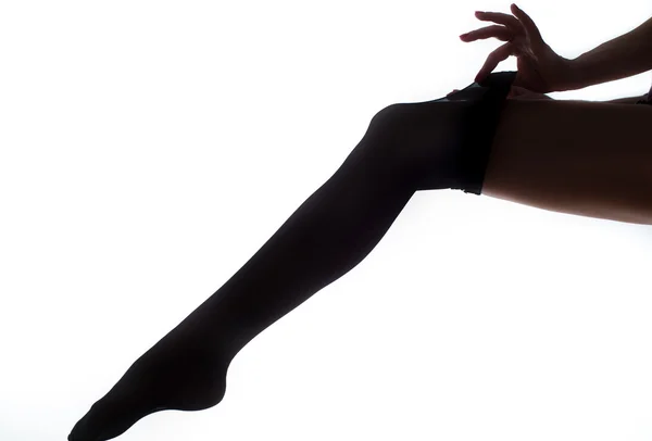 Lady puts on stockings in silhouette — Stock Photo, Image
