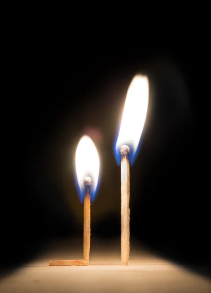 Burning match kneeling before match on fire metaphor — Stock Photo, Image