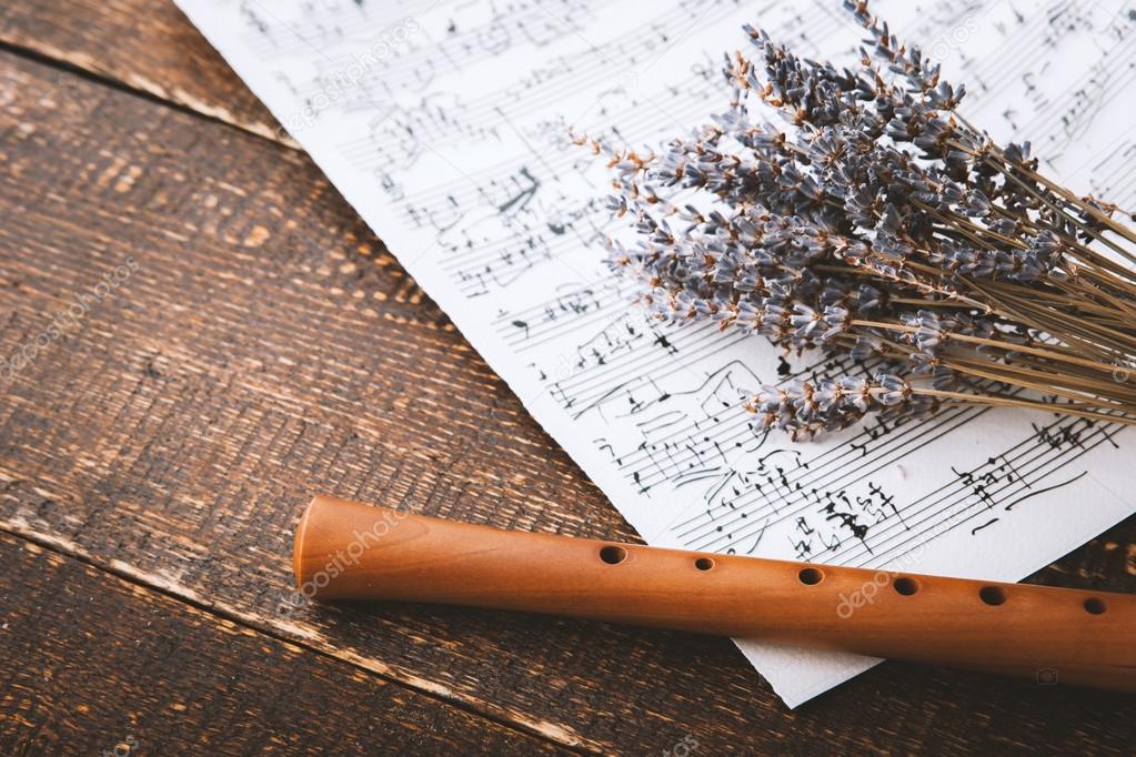 Flute with notes and lavender on the wooden table
