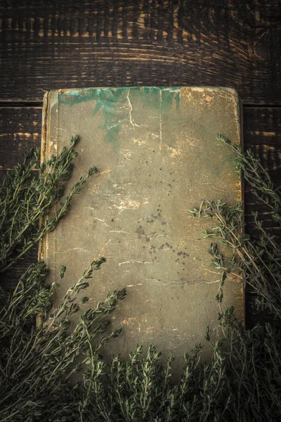 Old book with thyme on the wooden table vertical — Stock Photo, Image