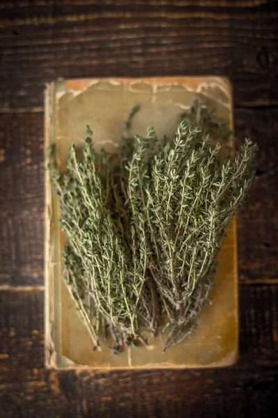 Vieux livre de cuisine avec thym sur la table en bois vertical — Photo