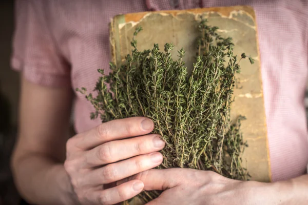 女人抱着旧食谱书和草药水平 — 图库照片