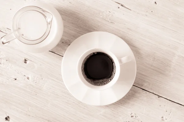 Чашка кави з глечиком молока на білому столі вид зверху — стокове фото
