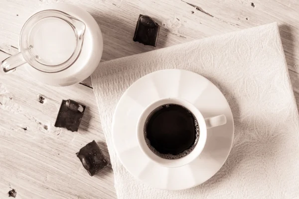 Xícara de café com jarro de leite e chocolate na vista superior da mesa branca — Fotografia de Stock