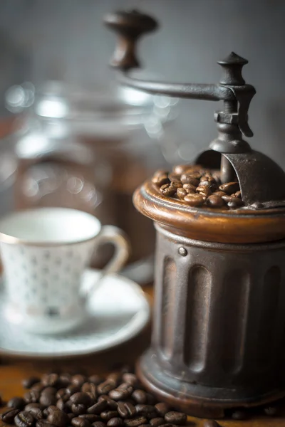 Coffee mill with coffee beans and blurred cup vertical — Stock Photo, Image