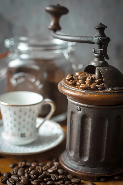 Coffee mill with coffee beans and blurred cup — Stock Photo, Image