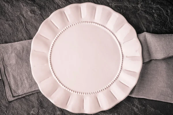 Біла тарілка на столі з темного каменю вид зверху — стокове фото