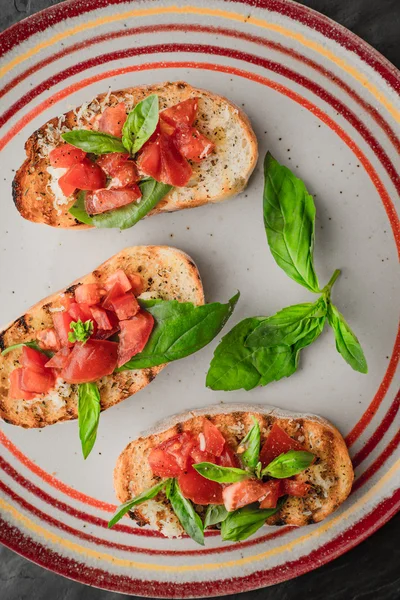 Bruschetta com tomates e manjericão na placa de cerâmica colorida — Fotografia de Stock