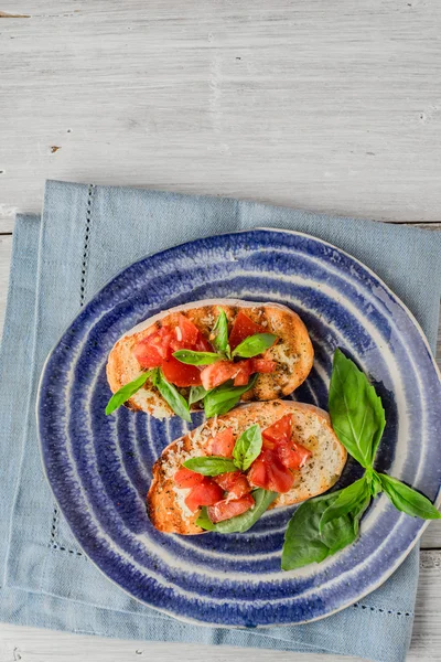 Bruschetta with tomatoes and basil on the ceramic plate vertical — Stock Photo, Image