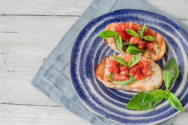 Bruschetta paradicsommal és basil, a vízszintes kerámia tányér — Stock Fotó