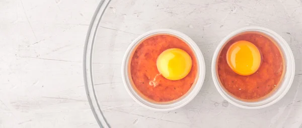 Råa ägg med tomater i ramekins på skärmen vit träbord brett — Stockfoto
