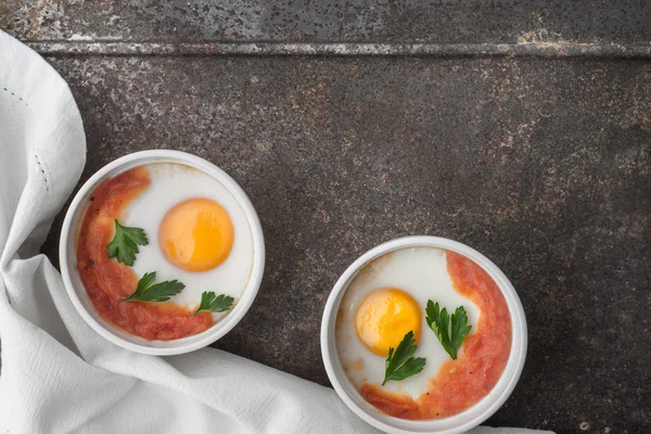 Domates ve maydanoz metal arka plan üstten görünüm üzerinde ramekins içinde yumurta pişirdim — Stok fotoğraf