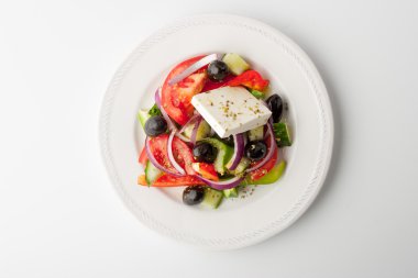 Beyaz zemin üzerinde bir seramik tabak içinde Yunan salatası