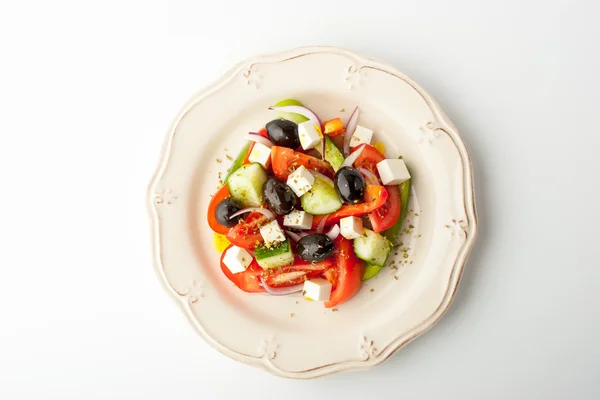 Ensalada griega en un plato de alivio sobre un fondo blanco —  Fotos de Stock