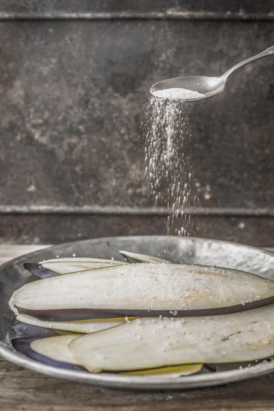 Posypując solą na plasterki bakłażanów — Zdjęcie stockowe