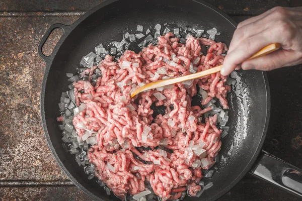 切成片的洋葱在锅中用木勺手中的原始肉末 — 图库照片