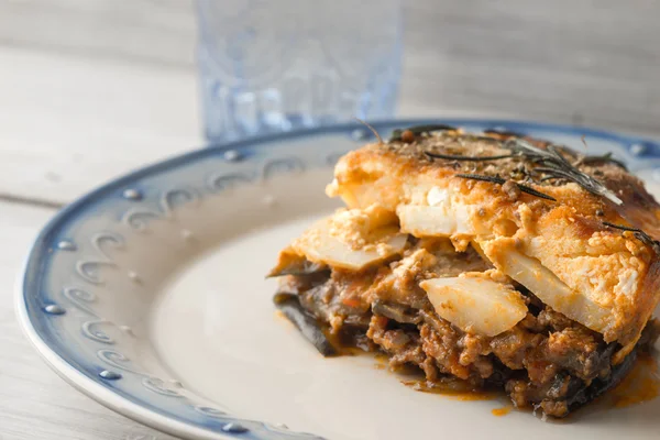 Piece of moussaka on the ceramic plate on the white table horizontal — Stock Photo, Image