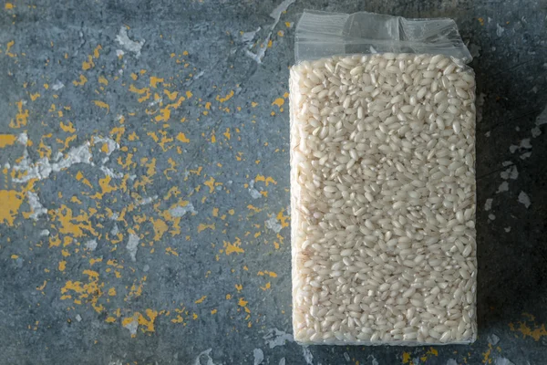 Verpackung mit Arborio-Reis auf altem blauen Hintergrund — Stockfoto