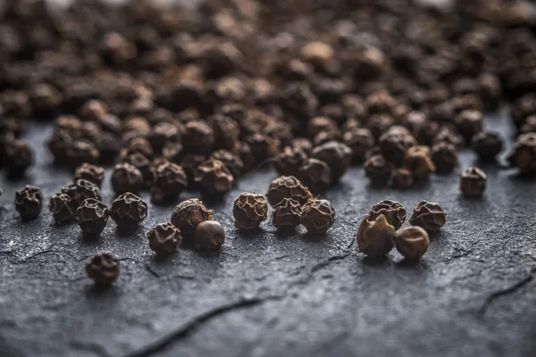 Erwten van zwarte peper op een grijze leisteen — Stockfoto