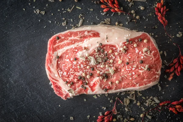 Bit av ribeye steak marmor, pepparkorn och salt på en skiffer blu — Stockfoto