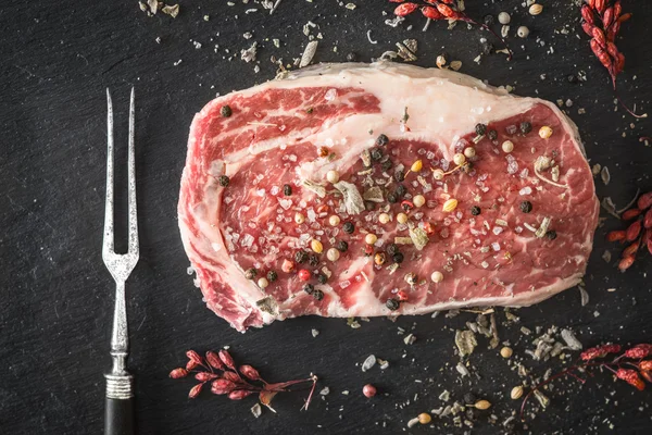 Trozo de bistec de ribeye mármol, tenedor y bayas de agracejo en un blu —  Fotos de Stock