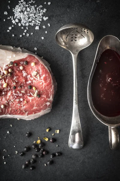 Filete de ribeye de mármol, enebro, cuchara, bote de salsa y sal en un — Foto de Stock