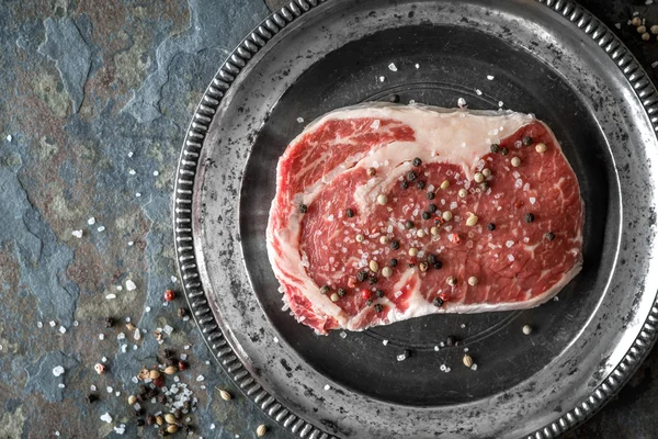 Piece of ribeye steak marble and peppercorn on a plate of tin — ストック写真