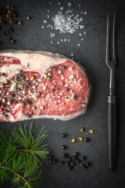 Marble ribeye steak, juniper, larch branch and fork on blue-blac — Stockfoto