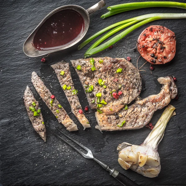 Strips of grilled ribeye steak sauce, onion, garlic and tomatoes — Stockfoto