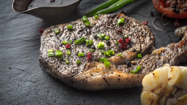 Grilovaný steak, omáčka, česnek a rajčata na kameni — Stock fotografie