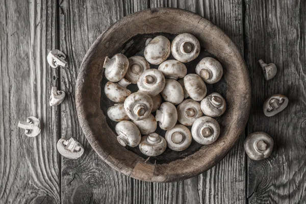 Champignon na tigela de madeira na vista superior da mesa velha — Fotografia de Stock