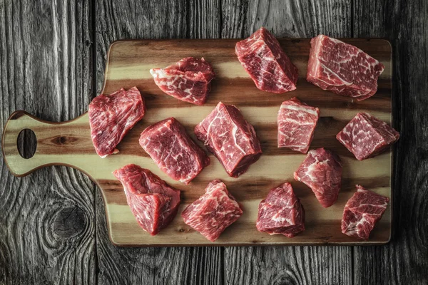 Trozos de carne cruda angus en la vieja mesa de madera horizontal — Foto de Stock