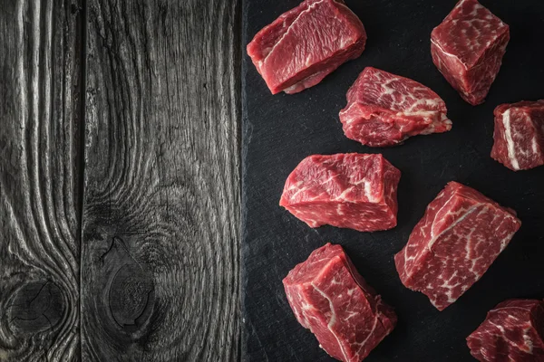 Rebanadas de carne cruda angus en la piedra negra en la mesa de madera horizontal —  Fotos de Stock