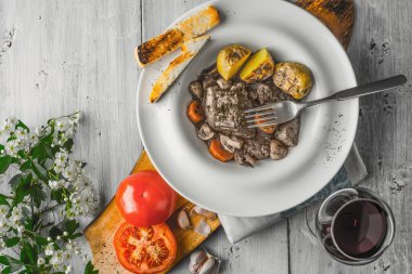 Bir seramik tabak, kırmızı şarap ve beyaz çiçekler içinde ederim