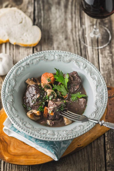 Beef bourguignon in a ceramic dish on a chopping board — Stock Photo, Image