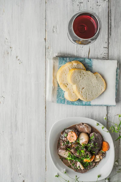 Bourguignon carne en un plato de cerámica con rebanadas de baguette y un — Foto de Stock