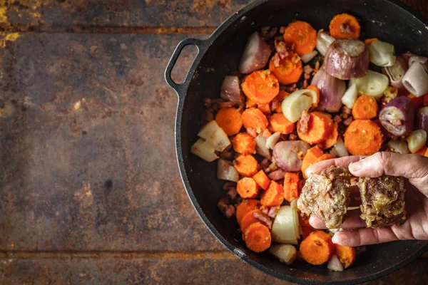 Adding  fried meat in the pan with carrots and shallot top view — Stock Photo, Image