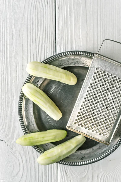 Peeled cucumbers in the metal plate with grater top view — Stock Photo, Image