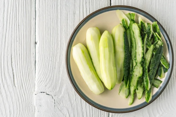 Peeled cucumbers in the ceramic plate  on the white table top view — Stock Photo, Image