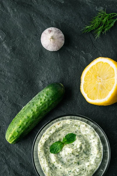 Tzatziki na temný kamenný stůl s přísadami — Stock fotografie