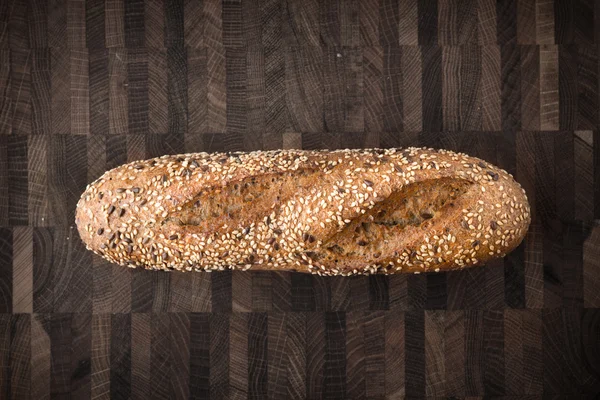 Brood met granen en zaden op de houten plank bovenaanzicht — Stockfoto