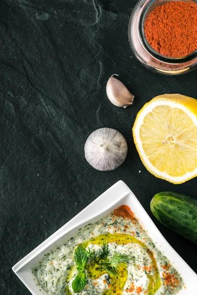 Tzatziki sul tavolo di pietra con verdure e condimento verticale — Foto Stock