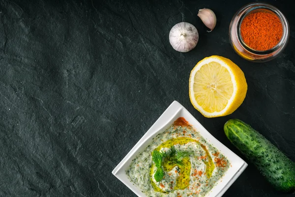 Tzatziki en la mesa de piedra con verduras y condimentos vista superior —  Fotos de Stock