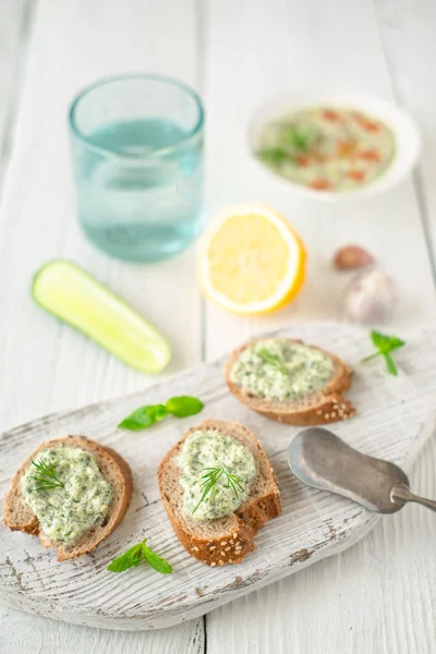 Pão com tzatziki na mesa de madeira branca vertical — Fotografia de Stock