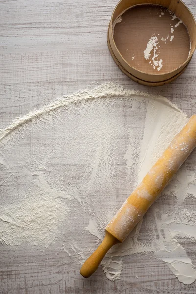 Farinha de trigo, rolo e peneira na mesa — Fotografia de Stock