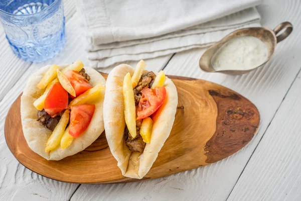 Gyros con patatas, carne, pan de pita y tomate en un bote de salsa — Foto de Stock