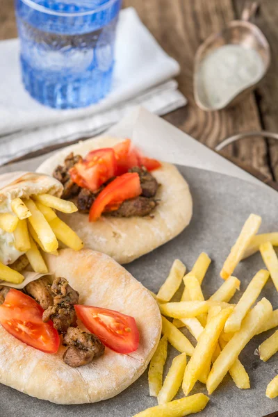 Gyros with potatoes, meat, tomato on pita bread, parchment and d