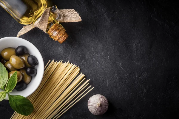 Σπαγγέτι, ελιές και ελαιόλαδο στο μαύρο πέτρινο τραπέζι — Φωτογραφία Αρχείου