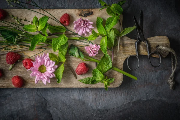 Flores, framboesas e hortelã na tábua de madeira — Fotografia de Stock
