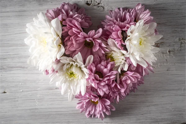 Coração feito de flores no fundo de madeira branca vista superior — Fotografia de Stock